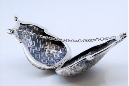 Caixa de comprimidos em prata guilhochada em forma de bolsa com corrente e fecho basculante.